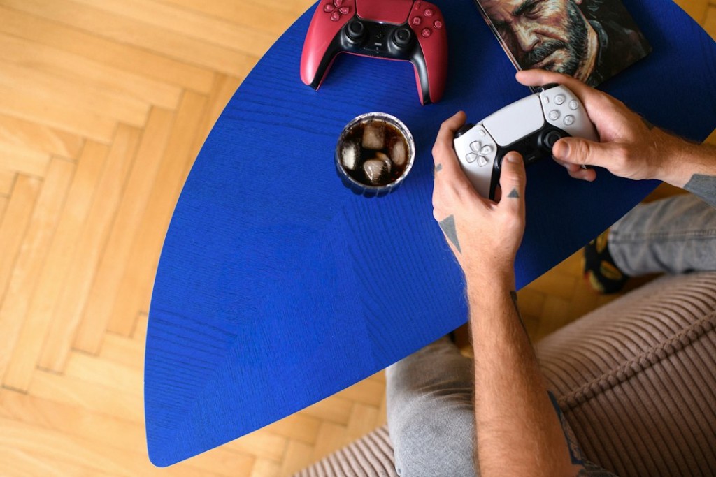 Pessoa adulta jogando videogame sentada à mesa com controle