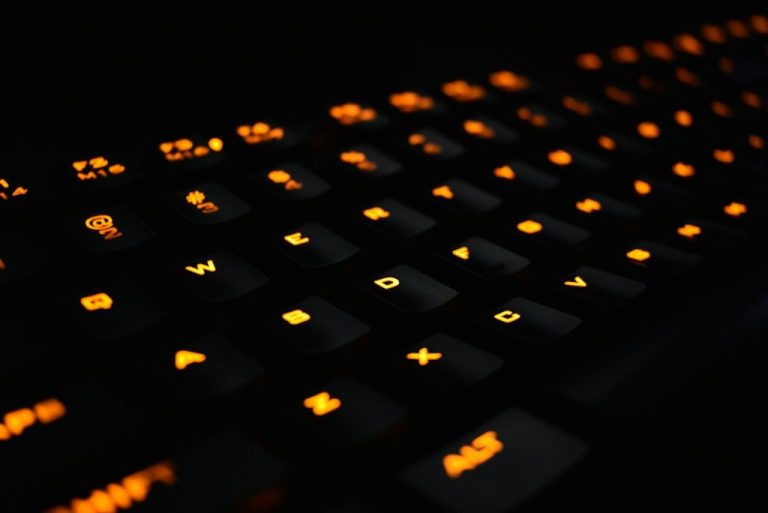 Teclado gamer com iluminação laranja em ambiente escuro