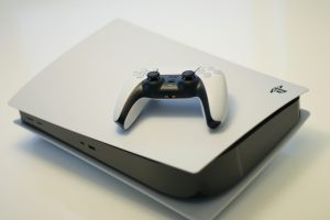 Console PlayStation 5 deitado com controle DualSense branco, fotografia ilustrativa da atualização de firmware 14.10
